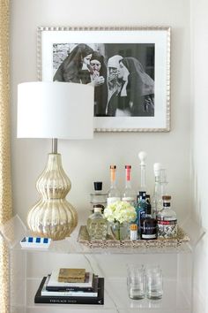 a shelf with bottles, glasses and pictures on it