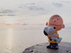 a statue of a person holding a dog on top of a rock near the water