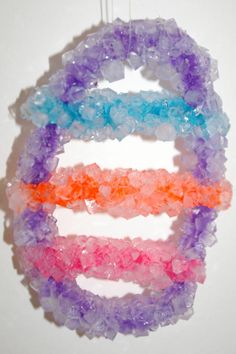 four different colored beads hanging from a hook on a wall ornament, with the letter e in the middle