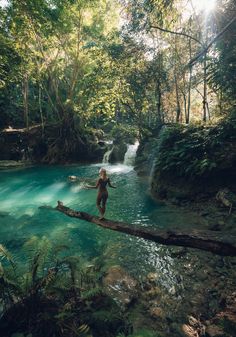 a person standing on a log in the middle of a river with water running over it