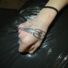 a person with a tattoo on their arm holding onto a black plastic bag and wearing a bracelet