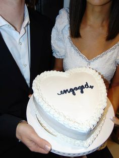 a man and woman holding a heart shaped cake