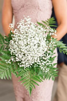 the bride and groom are standing next to each other holding their bouquets with baby's breath