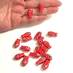 a hand is holding some red beads with eyes on them