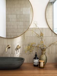 a bathroom with two round mirrors on the wall and a vase filled with flowers next to it