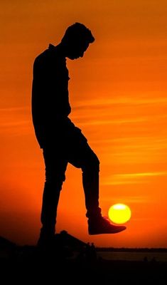 the silhouette of a person jumping in the air with their feet up against an orange and yellow sky