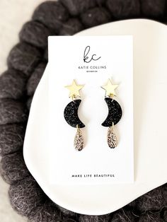 Welcome to Katie Collins Design Co. How cute are these celestial inspired gold star and crescent moon dangle earrings! Handmade from polymer clay, the moon features black clay with gold glitter to give it that extra celestial feel with a delicate teardrop covered in textured gold foil. Attached to beautiful gold brass star earring posts, these dangles are absolutely perfect to wear for this years much anticipated solar eclipse. Not to mention they would be the perfect gift for any astrology lover, science teacher or star gazing friend in your life! Truly one-of-a-kind, all of my earrings are lovingly handmade by me with extremely lightweight polymer clay and come on pretty jewelry cards making them perfect to gift. I also offer FREE shipping on all orders over $35 as well as a FREE gift wi Moon Earrings Clay, Moon Clay Earrings, Polymer Clay Moon, Holiday Jewelry Ideas, Moon Clay, Collins Design, Clay Moon, Star Dangle Earrings, New Eve