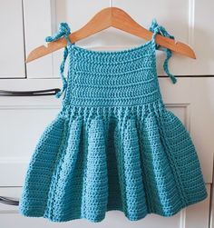 a blue crocheted dress hanging on a wooden hanger