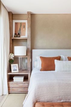 a white bed sitting next to a wooden shelf with pictures on top of it in a bedroom