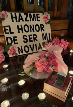 flowers and candles are placed in front of a sign that reads hazme el honor de ser mi novice