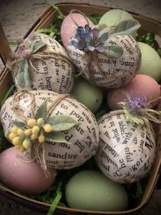 several decorated eggs in a box with some flowers on top, and an old book page