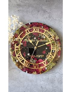 a decorative clock with flowers on the face and numbers in gold, red and black