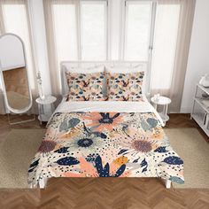 a bed with floral comforter and pillows in a room next to a mirror on the wall