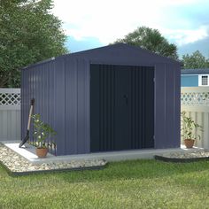 a garden shed sitting on top of a lush green field next to a white fence