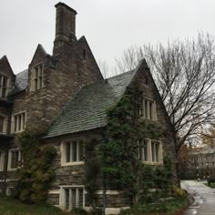 an old stone house with ivy growing on it's roof and windows in the front