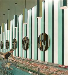 a woman is shopping for food in a grocery store with striped walls and hanging lights