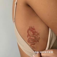 a woman with a dragon tattoo on her back and shoulder, showing it's red ink