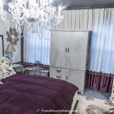 a bedroom with purple bedding and chandelier