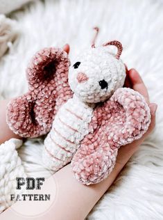 a hand holding a pink and white crocheted teddy bear