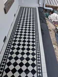 a black and white checkered tile floor in front of a house with an open door