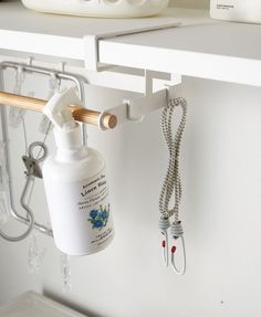 a bottle hanging from the side of a white shelf next to a phone and ear buds