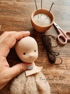 someone is making a doll out of felt and yarn with scissors on the table next to it