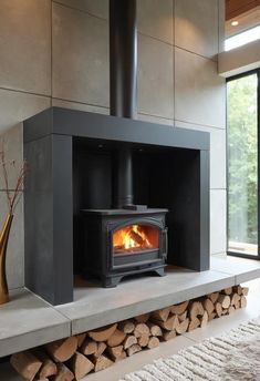 a wood burning stove in a living room next to a pile of firewood and a vase