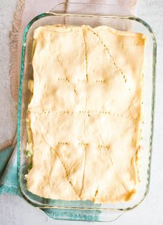 an uncooked pie in a glass dish on a white table with a blue towel