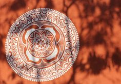 an orange and white plate sitting on top of a wooden table next to a tree