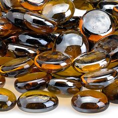 some brown and black glass pebbles on a white surface with water droplets in the middle