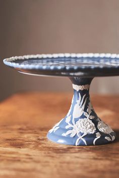 a blue and white cake plate sitting on top of a wooden table next to a wall