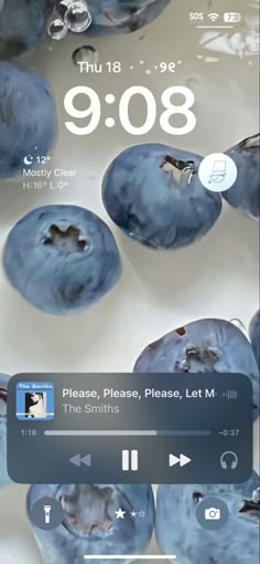 an iphone screen with blueberries floating in the water and music player on it's side