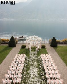 an outdoor wedding set up with white and pink flowers on the grass, overlooking water