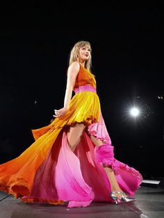 a woman in a colorful dress is standing on the runway with her legs spread out