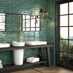 two white sinks sitting under a mirror in a bathroom next to a green tiled wall