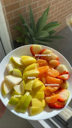 a white plate topped with sliced fruit on top of a window sill next to a potted plant