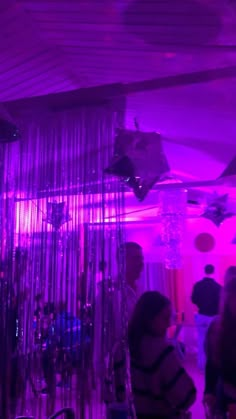 people are standing in a room with purple lights and chandeliers hanging from the ceiling