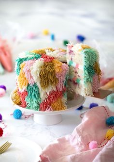 a colorful cake on a white plate with a knife and fork in the foreground