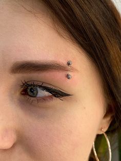 a woman with piercings on her forehead and eyeliner is looking at the camera