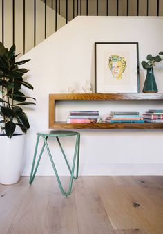 there is a plant and some books on the shelf next to it in this room