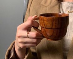 a woman holding a wooden cup in her hands