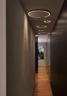 a long hallway with lights on the ceiling and wood flooring in front of it