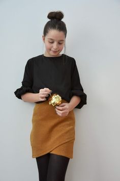 a girl in black shirt and brown skirt holding a gold object