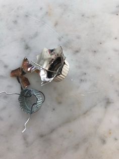 two pieces of metal sitting on top of a white marble floor next to each other