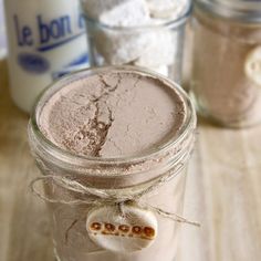 three jars with different types of food in them sitting on a table next to milk