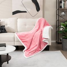 a living room with a white couch and a pink blanket on the back of it