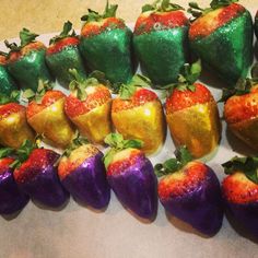 there are many chocolate covered strawberries on the counter top, with green and red decorations