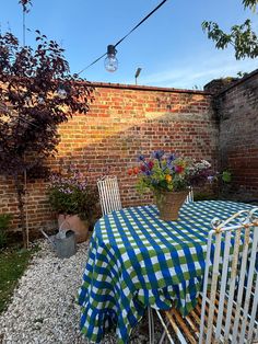 a table and chairs are set outside by the brick wall