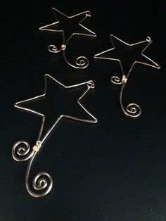 three star shaped earrings sitting on top of a black surface with swirls in the middle