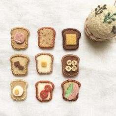 miniature food items are displayed on a white tablecloth next to a ball of thread